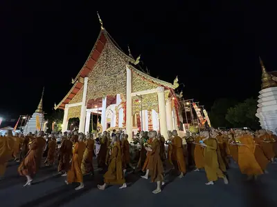 Line of monks circumambulating the illuminated hall at Wat Chedi Luang on Asalha Puja 2026