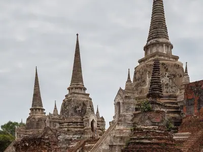 Chedis of Wat Phra Si Sanphet with a monk walking past in orange robes