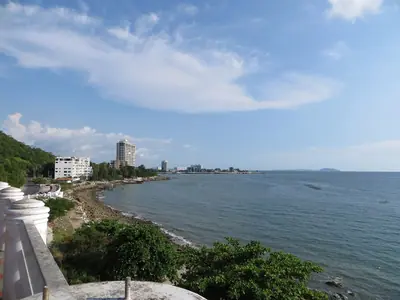 The coast at Bang Saen with sea, trees and a wall under a blue sky