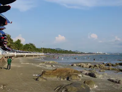 Rocky foreshore at Bang Saen with a few people on the beach