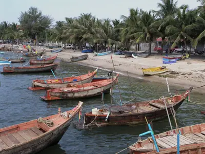 Thai fishing boats pulled up on the beach under palm trees