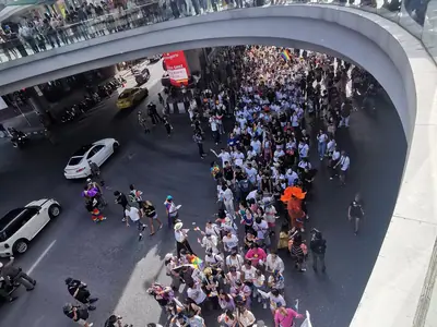 Crowds of marchers pack a road beneath an elevated walkway during the Bangkok Pride Parade 2023 at ONESIAM