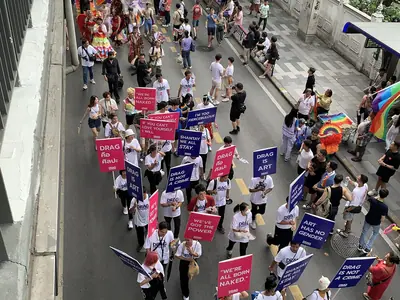 Aerial view of the Bangkok Pride 2024 parade with pink banners moving along the street