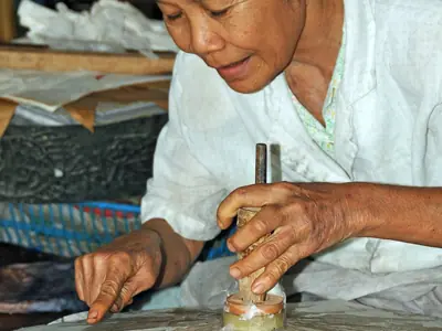 A woman glues paper onto an umbrella frame at an umbrella workshop near Chiang Mai
