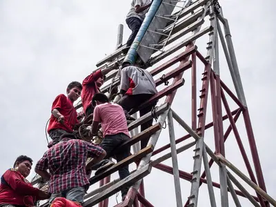 Mannen klimmen op de steiger van een gigantische bamboeraket-lanceertoren tijdens het Yasothon Rocket Festival (2013)