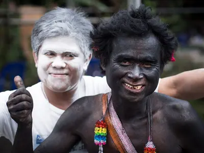 Twee lachende deelnemers met beschilderde gezichten, een in zwarte verf, bij de optocht van het Yasothon Rocket Festival (2013)