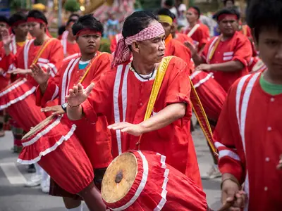 Trommelaars in rode kostuums treden op in de optocht van het Yasothon Rocket Festival (2013)