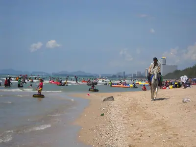 Bezoekers en een ruiter op het brede strand van Cha-am in 2010