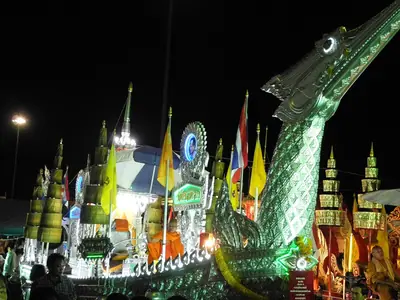 An illuminated naga-headed Chak Phra festival boat at night in Surat Thani