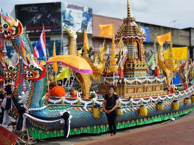 A Chak Phra festival boat decked out in colourful ornaments and flags being pulled through the street in Surat Thani