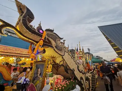 A gilded Chak Phra float rolling through a crowded street in Surat Thani (15 October 2022)