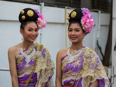 Twee jonge vrouwen in traditionele Lanna-kleding met bloemen in het haar wachten om aan te sluiten bij de optocht van het Chiang Mai Flower