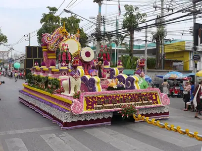 Een met kleurrijke bloemen bedekte praalwagen rijdt door een straat in Chiang Mai tijdens het Flower Festival