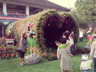 Visitors by a flower-covered arch at the Chiang Rai Flower Festival