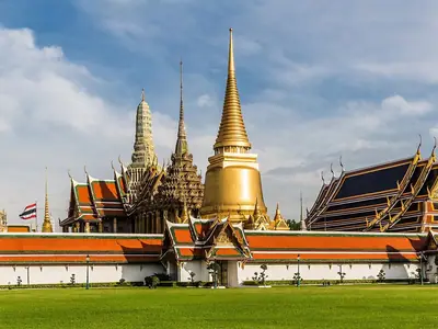 Silhouet van gouden chedi's en betegelde daken van Wat Phra Kaew, gezien over het gazon