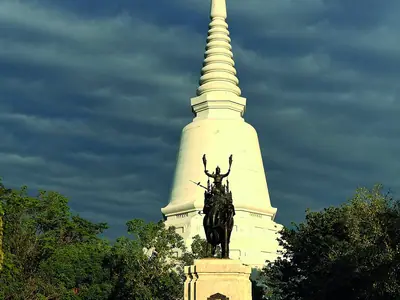 White chedi and monument at Don Chedi, Suphan Buri, seen from below against a dramatic sky