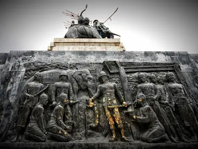 Relief carving of warriors at the Don Chedi Monument with a statue group on top