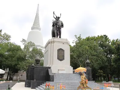 Don Chedi Monument with the king statue and white chedi surrounded by trees