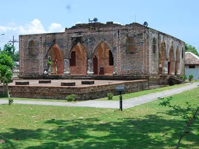 Historic Krue Se Mosque in Pattani: a brick building with arched openings, seen across a lawn