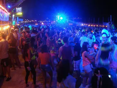 Dancing crowd lit by blue and green lights at the Full Moon Party on Haad Rin beach (2016)