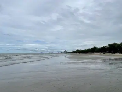 Quiet Hua Hin beach with wet sand and dark clouds