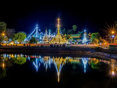 Wat Chong Klang lit up at night across the lake in Mae Hong Son