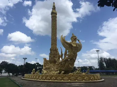Replica of a Candle Festival float in Thung Si Muang park, Ubon Ratchathani: a tall candle spire on a golden base under a blue sky