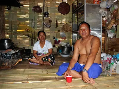 Inside a Lahu hill-tribe home near Chiang Rai: two people sit beside the cooking fire