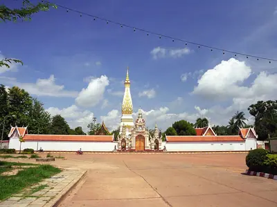 Wat Phra That Phanom in Nakhon Phanom province: a tall white-gold chedi behind a wall and a large forecourt