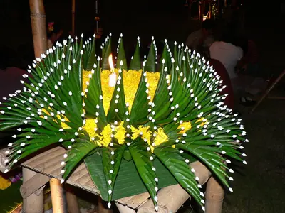 A banana-leaf krathong with pleated green leaves and yellow flowers at night (Chiang Mai, 2005)