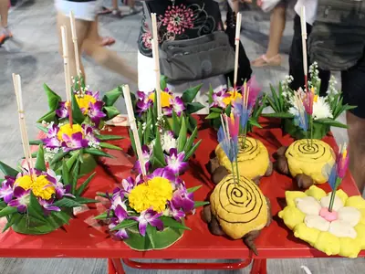 A street stall with banana-leaf krathongs decorated with orchids, candles and flowers (2015)
