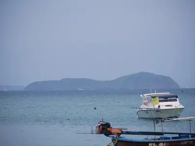Boats at anchor off Rawai Beach, Phuket, with a rocky island in the distance