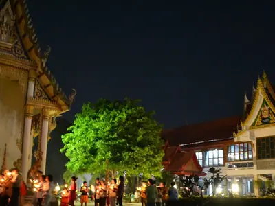 Candle-lit gathering at night in front of temple halls at Wat Khung Taphao on Makha Bucha day