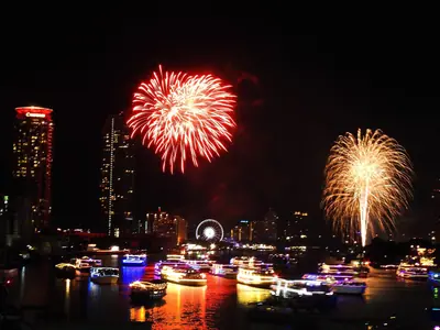 Red and gold fireworks over the Bangkok river with towers and a Ferris wheel in view (2019)