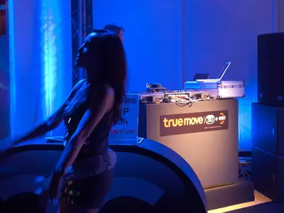 A woman dances behind a DJ desk in blue light at the Pattaya Music Festival