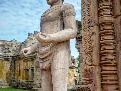 A stone guardian statue beside a carved doorway at Phanom Rung