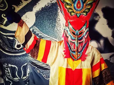 A Phi Ta Khon ghost mask in red and yellow with colourful patchwork costume in Dan Sai