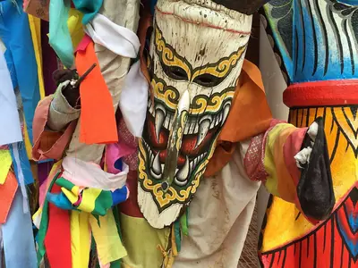 A Phi Ta Khon mask with a horned face and patchwork costume among other costumes in Dan Sai