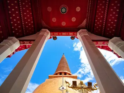 Looking up between red pillars at the golden dome of Phra Pathom Chedi