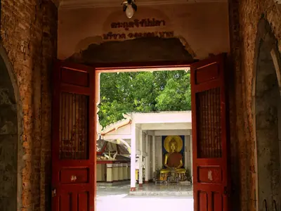 Red wooden doorway at Wat Phra That Phanom opening onto the courtyard