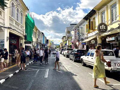 Pedestrians and cars on Thalang Road in Phuket Old Town lined with colourful shophouses