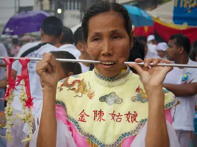 A woman in pink ceremonial dress with a flower garland in the Phuket Vegetarian Festival procession