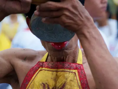 A participant in a yellow-and-red costume at the Phuket Vegetarian Festival