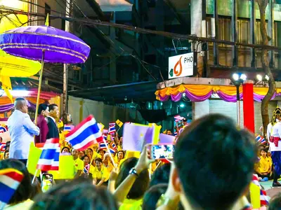 King Rama X and Queen Suthida greeted by crowds waving Thai flags and yellow umbrellas in Chinatown, Bangkok (2019)
