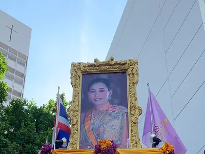 A framed portrait of the Queen on display with purple and gold drapery