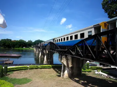 A train in blue and white crossing the bridge over the River Kwai