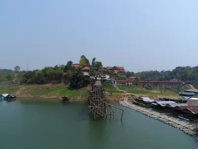 The Mon Bridge seen from the lake with houses on the far shore in Sangkhlaburi