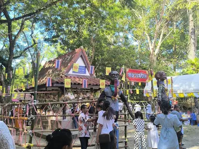 Visitors walking through temple grounds with offering stalls during Sat Duan Sip in southern Thailand