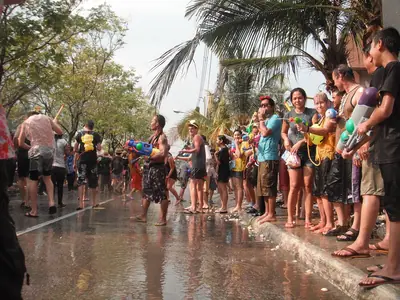 Crowd of people along a wet street during Songkran, many holding water guns