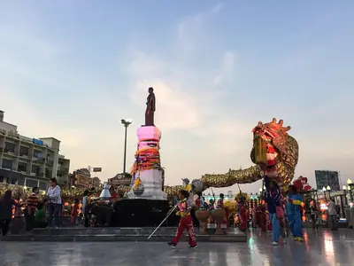 Festivalpodium met een versierd roze decor en een drakenfiguur bij het Thao Suranari-monument in Nakhon Ratchasima